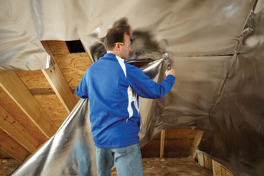 Professional installing radiant barrier in attic
