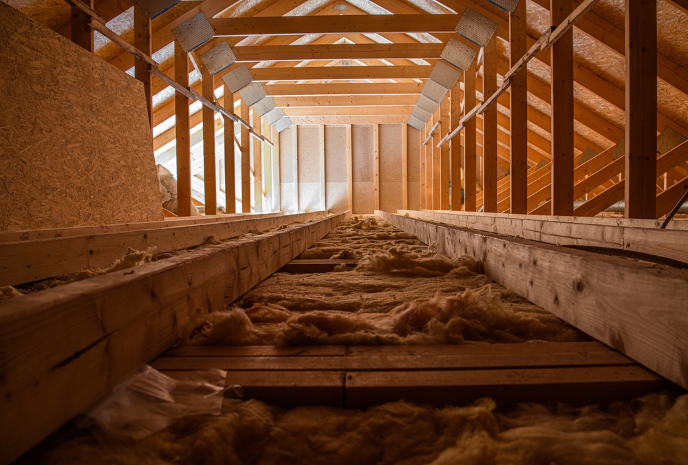 Empty loft space with exposed beams and natural light filtering through a window