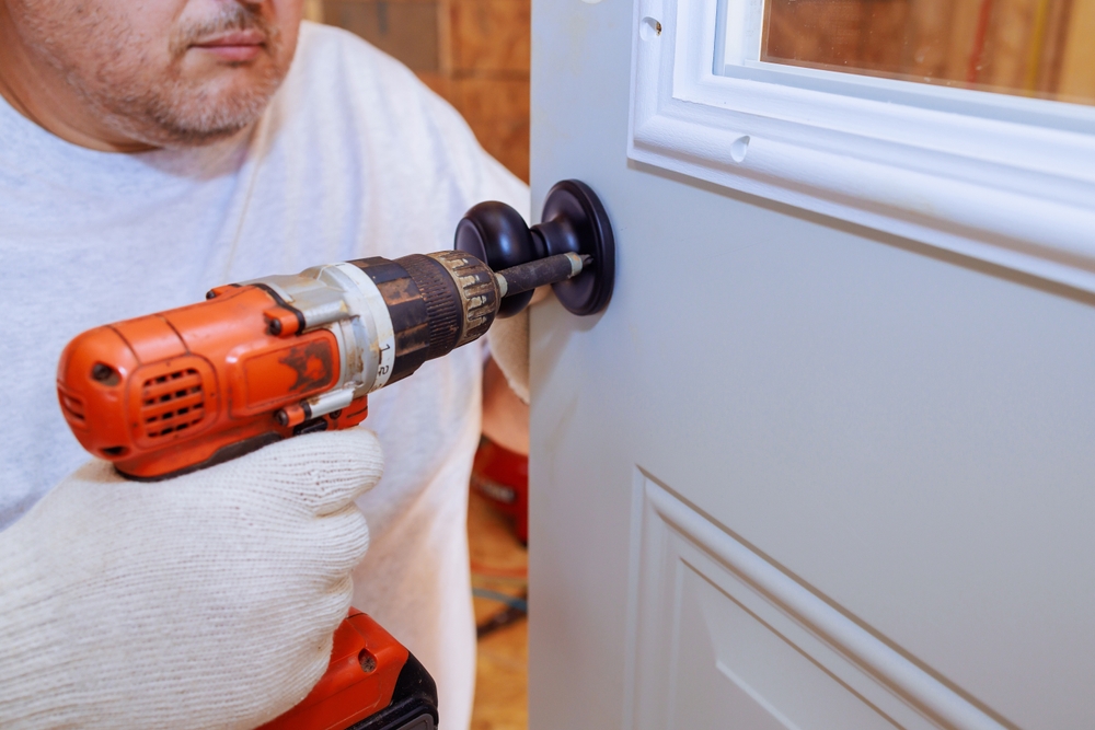 Professional locksmith in uniform holding a set of keys in front of a residential door
