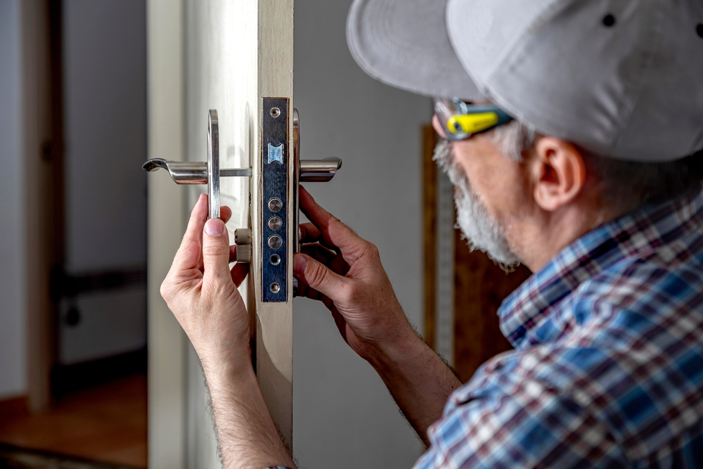 A locksmith assisting a homeowner with a lock installation on a front door.